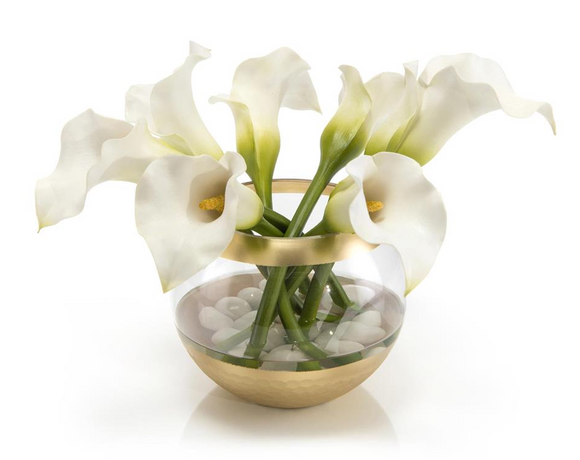 A white ceramic bowl filled with white calla lilies and decorative rocks.